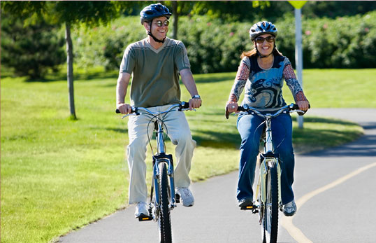 two people riding bikes along a bike path